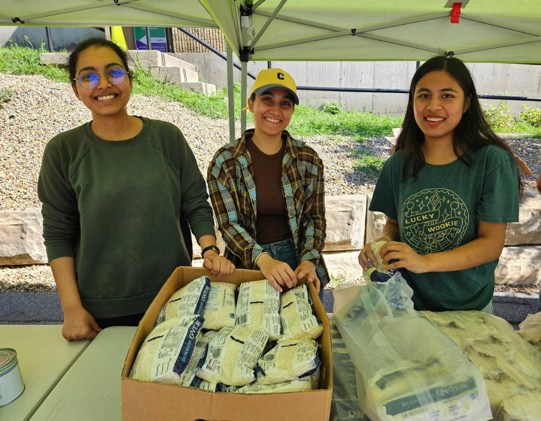 A group of three people behind a table with boxes of packaged food