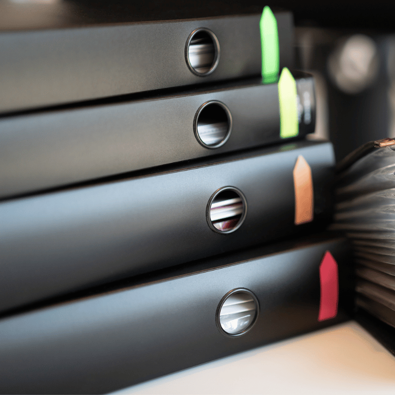 A stack of portfolio binders with different colored labels