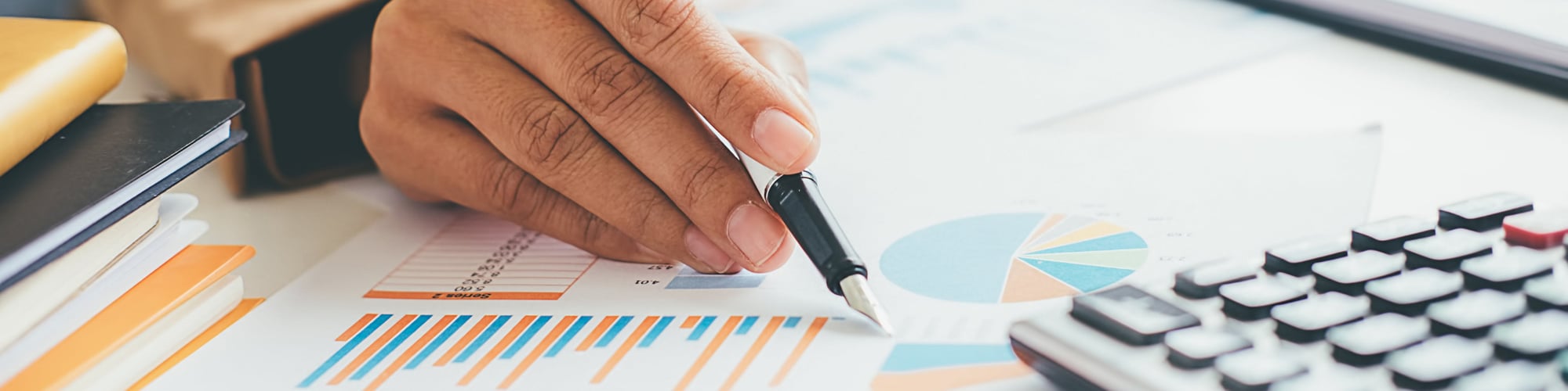 A person holding a pen pointing to a chart