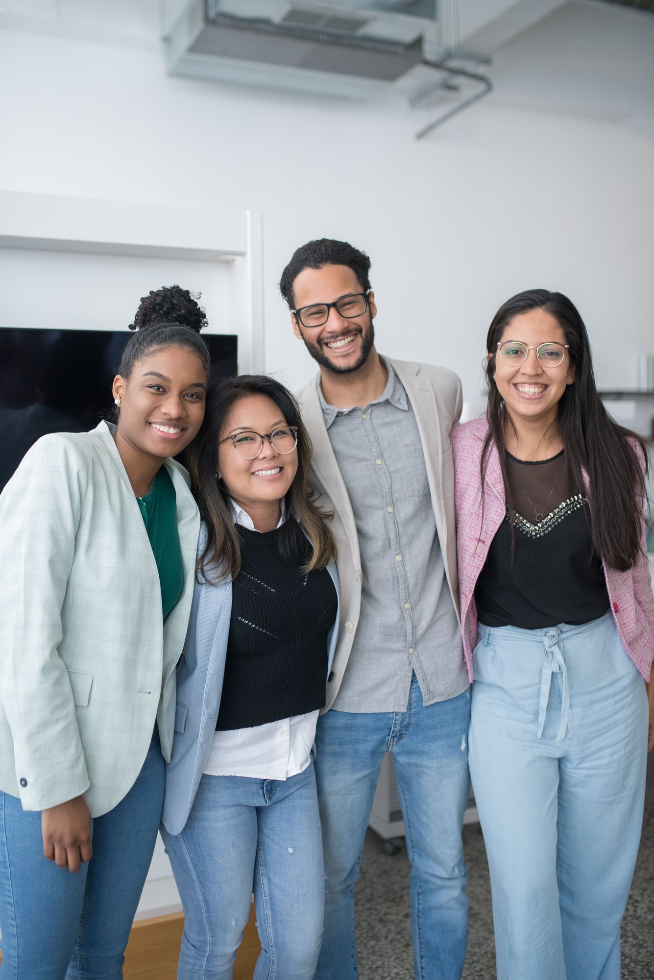 Group of diverse young professionals smiling in an office setting Group of diverse young professionals smiling in an office setting