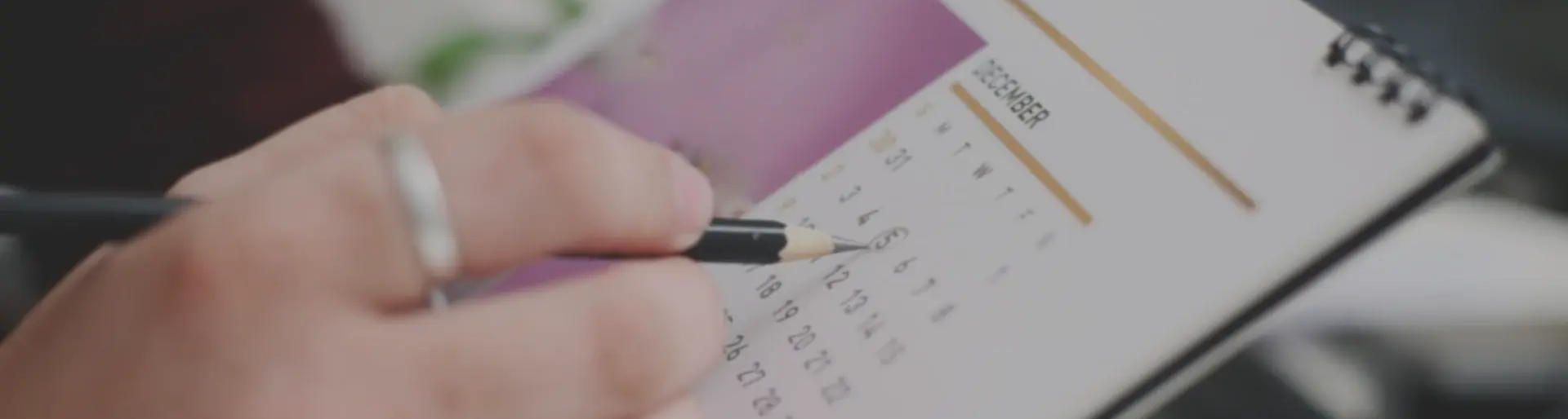 a person holding a pencil and pointing at a date on a calendar